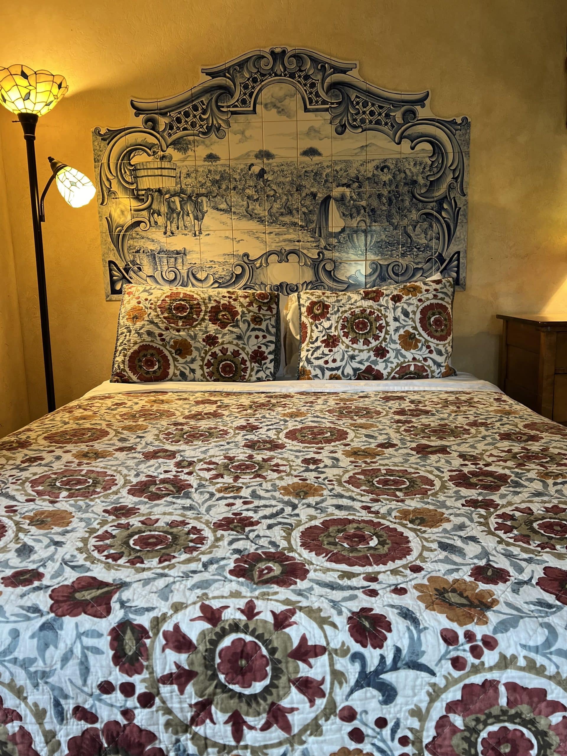 Vineyard-inspired guest bed with tile mural headboard at Blue Sky Vineyard.