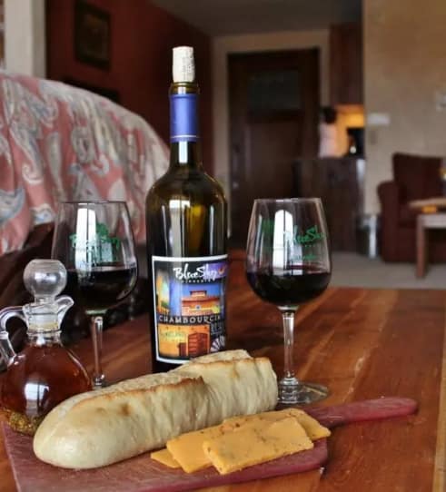 Wine, cheese, and ham tasting at Blue Sky Vineyard on a wooden table inside the suite.