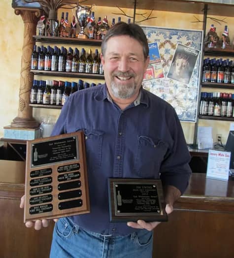 Winemaker holding awards at Blue Sky Vineyard tasting room.